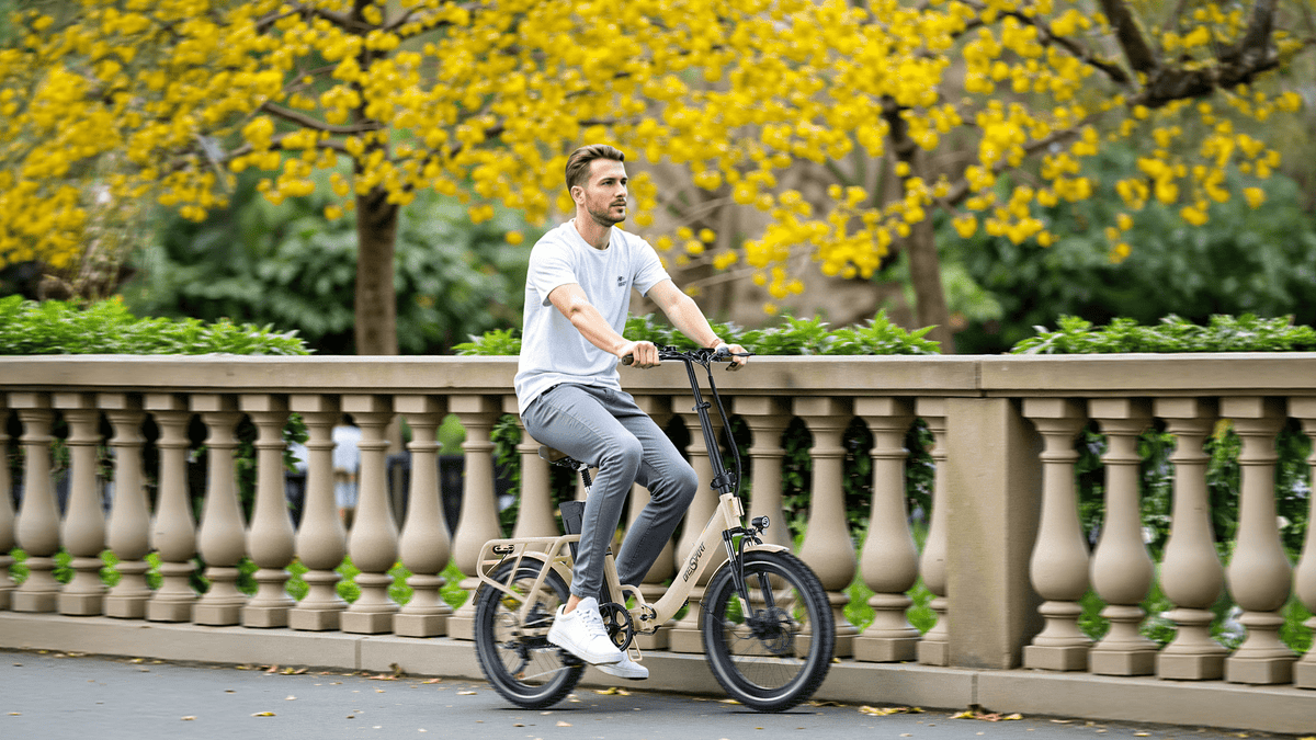 Hombre montando la bicicleta eléctrica plegable OneSport OT16-2 en color beige en un parque