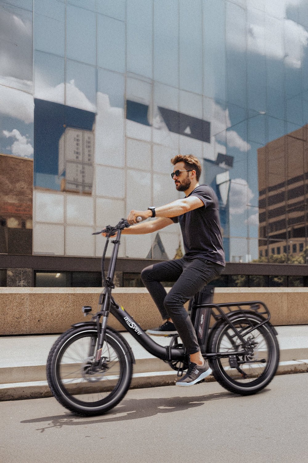 Hombre montando la bicicleta eléctrica plegable OneSport OT16-2 en color negro por una calle