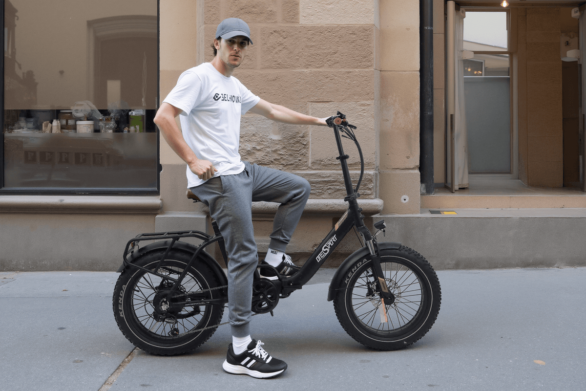 Hombre montando la bicicleta eléctrica plegable fat bike OneSport OT16 Max en color negro por una calle