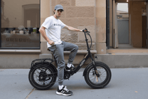 Hombre montando la bicicleta eléctrica plegable fat bike OneSport OT16 Max en color negro por una calle