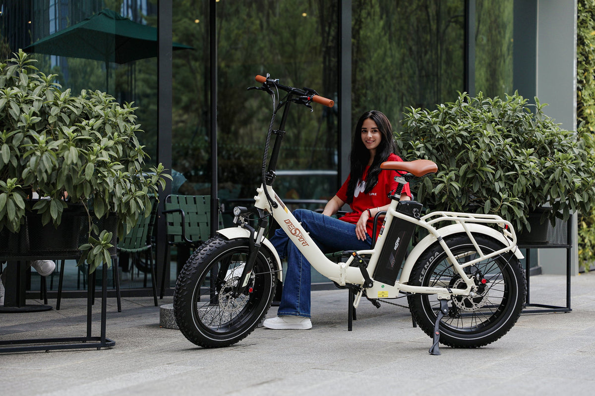 Mujer sentada en la bicicleta eléctrica plegable fat bike OneSport OT16 Max en color beige por una calle
