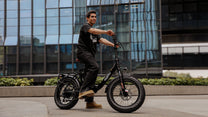 Hombre montando la bicicleta eléctrica plegable fat bike OneSport OT16 Max en color negro por la ciudad