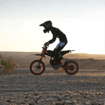Piloto saltando con la moto cross eléctrica Ridingtimes GT54 al atardecer