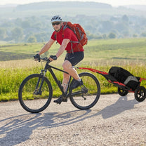 Persona en bicicleta remolcando el remolque de carga Smart por una carretera rural