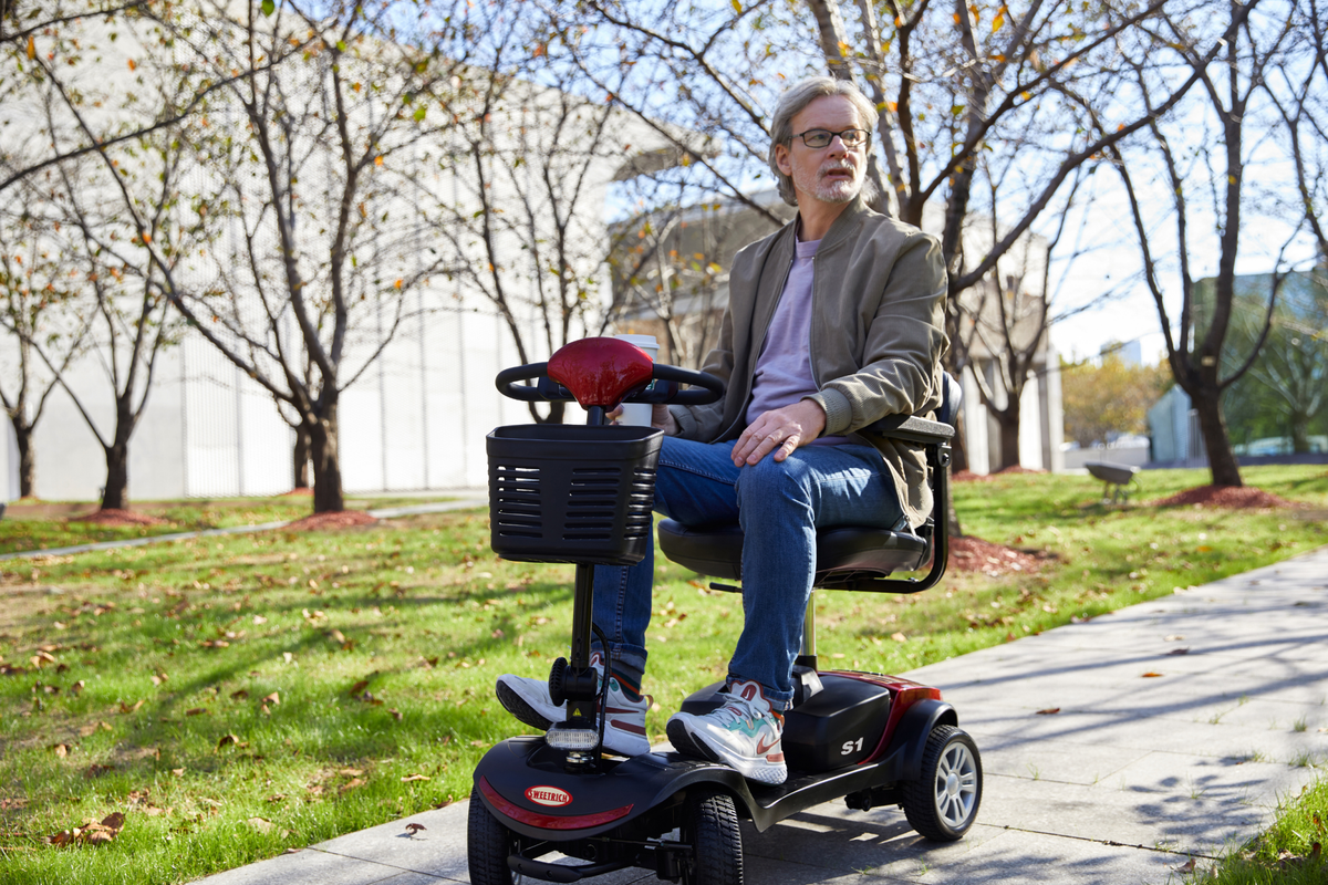 Hombre sentado en el scooter de movilidad Sweetrich S1 Sport en un parque