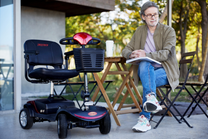 Persona sentada junto al scooter de movilidad Sweetrich S1 Sport