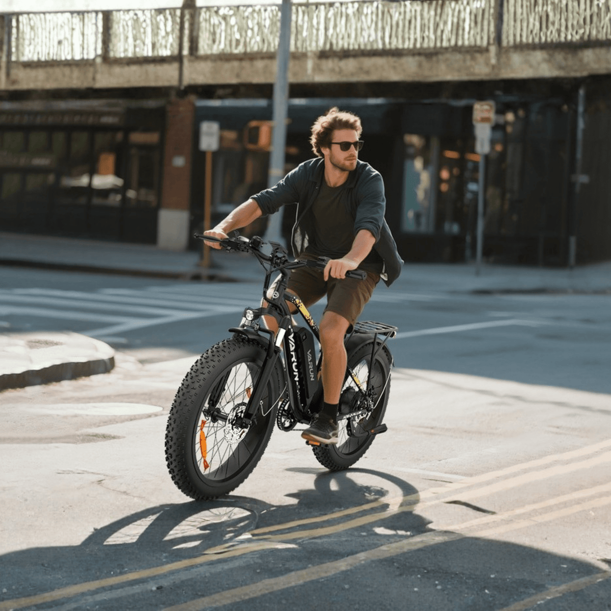 Hombre montando la bicicleta eléctrica fat bike VARUN M26-2 Plus en color negro por una calle