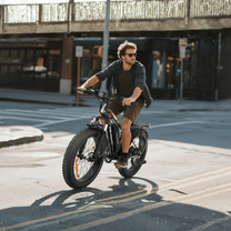 Hombre montando la bicicleta eléctrica fat bike VARUN M26-2 Plus en color negro por una calle