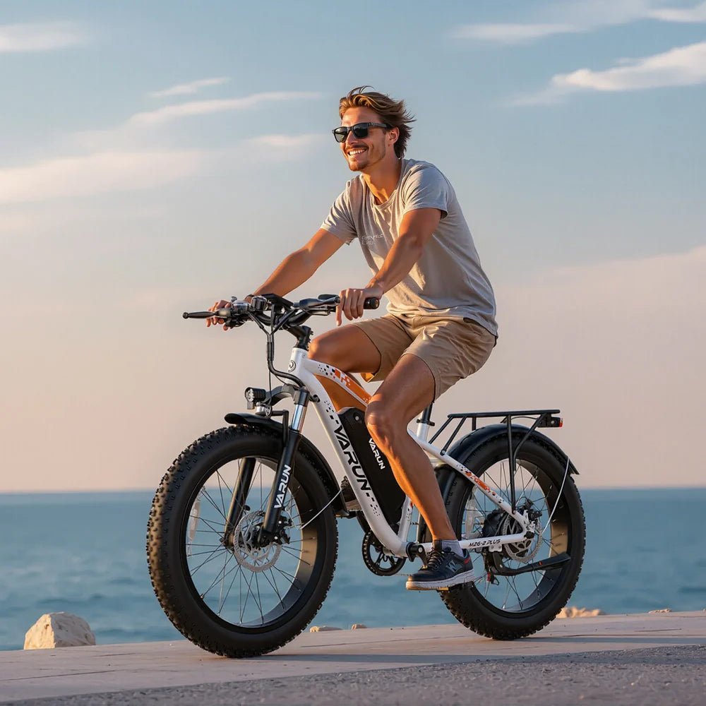 Hombre montando la bicicleta eléctrica fat bike VARUN M26-2 Plus en color blanco junto al mar