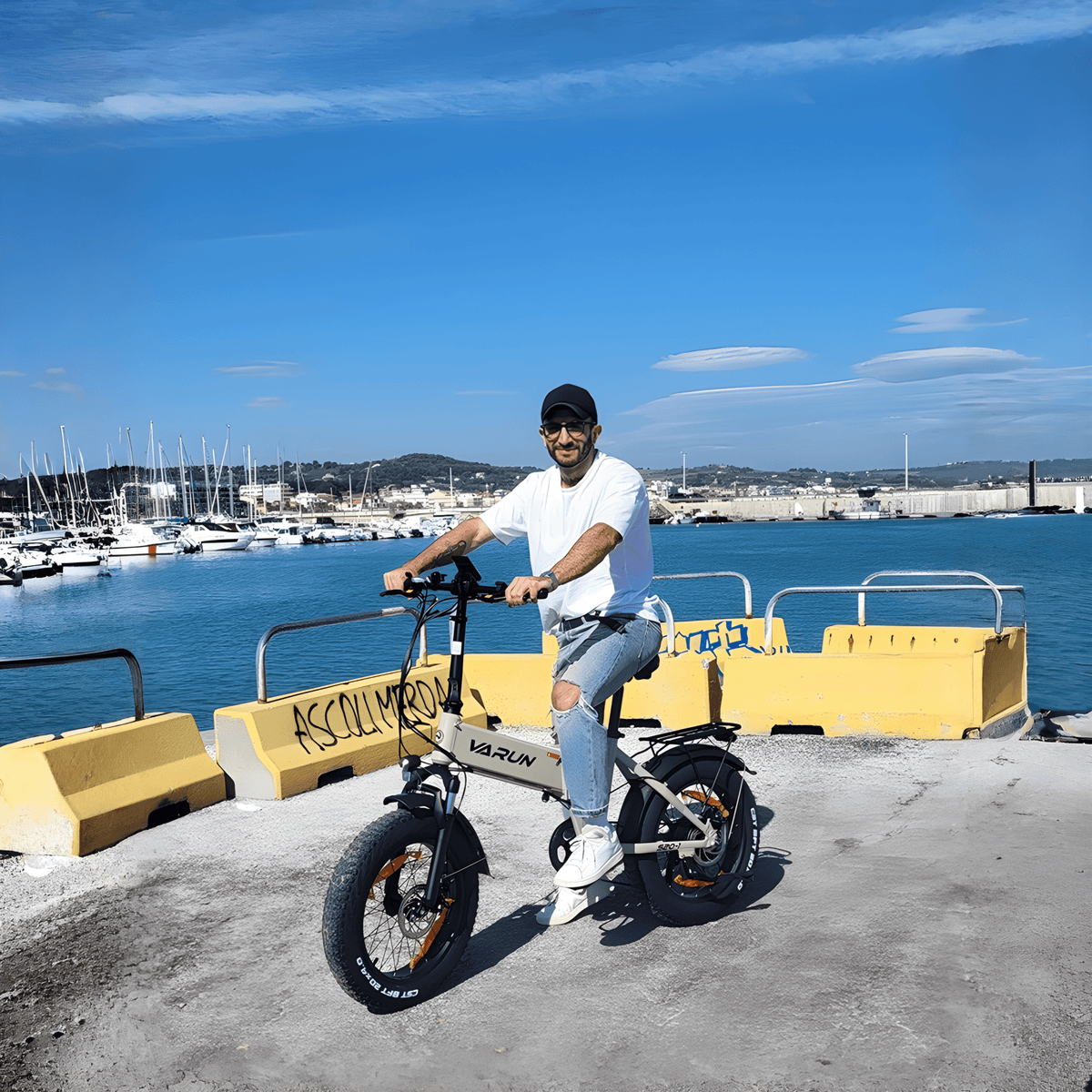 Hombre montando la bicicleta eléctrica plegable fat bike VARUN S20-1 en color beige junto al mar