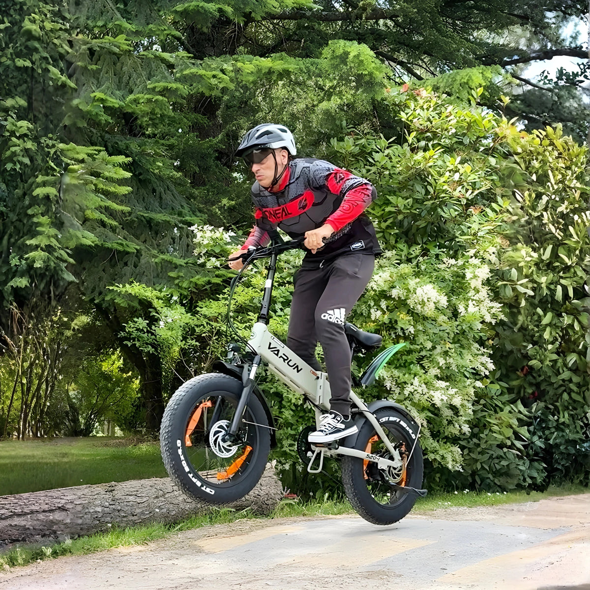 Hombre montando la bicicleta eléctrica plegable fat bike VARUN S20-1 en color beige con casco en el bosque