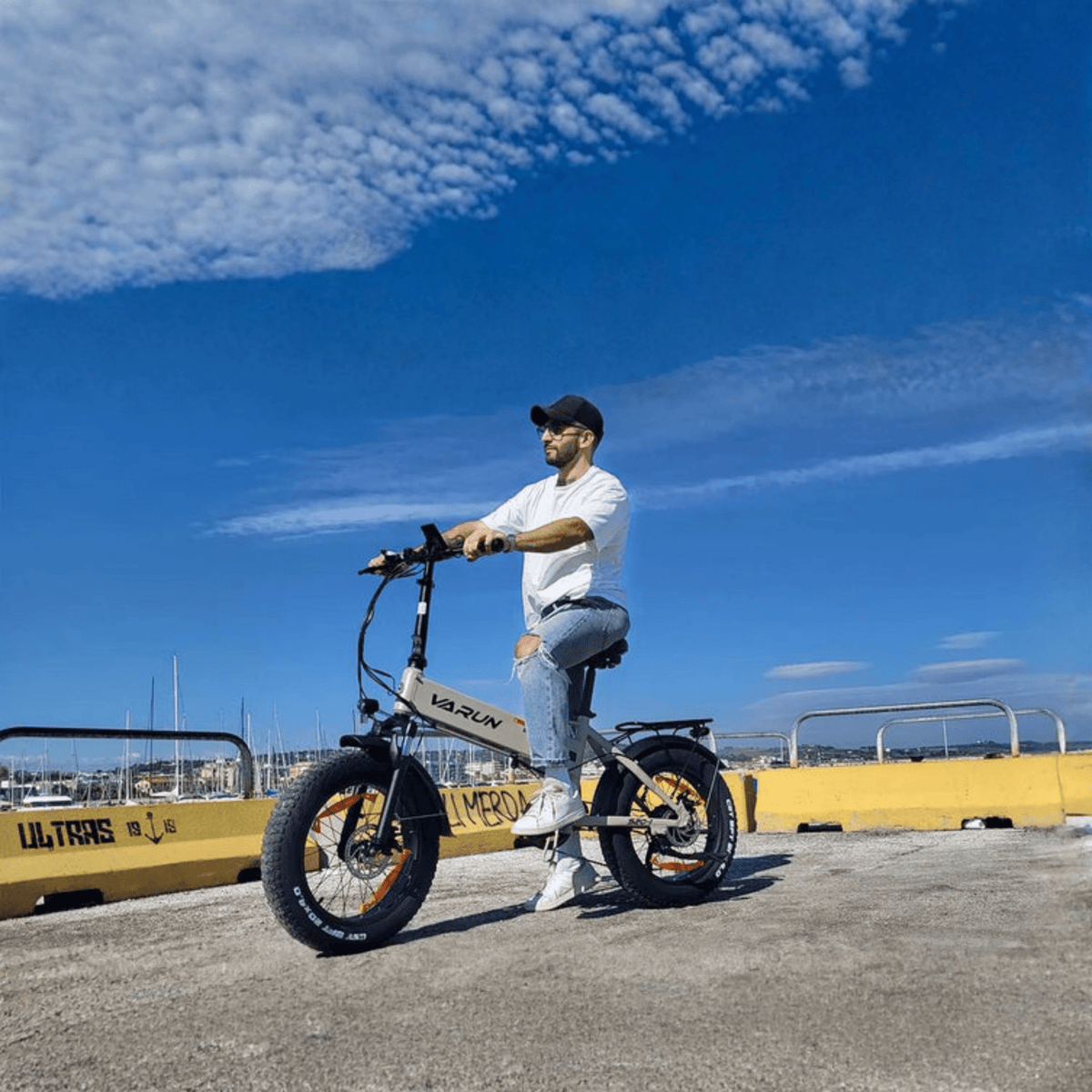Hombre montando la bicicleta eléctrica plegable fat bike VARUN S20-1 en color beige junto al mar