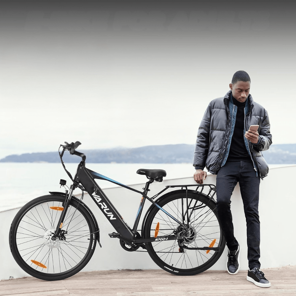 Hombre de pie junto a la bicicleta eléctrica VARUN S700-1 en color negro