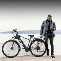 Hombre de pie junto a la bicicleta eléctrica VARUN S700-1 en color negro