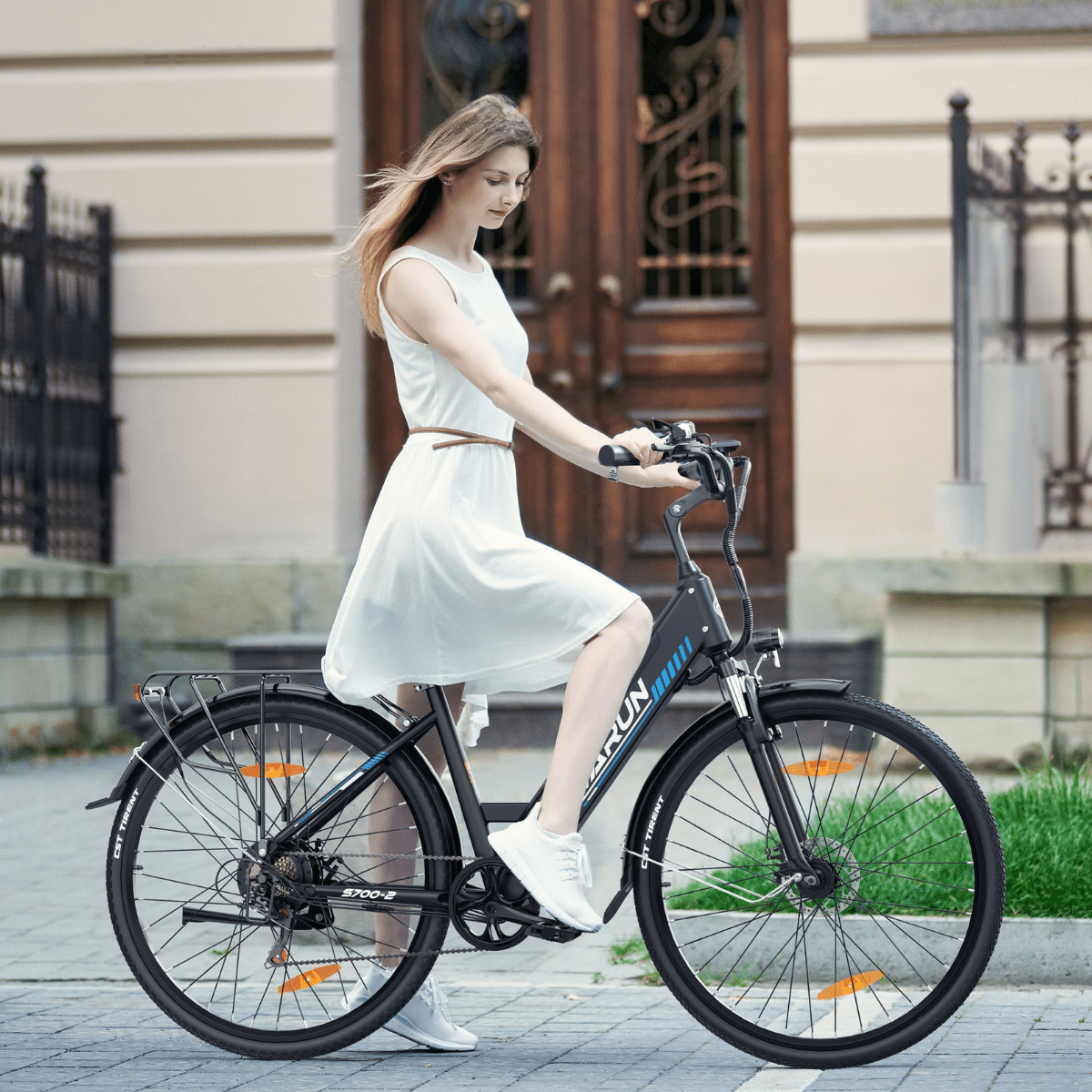 Mujer montando la bicicleta eléctrica VARUN S700-2 en color negro por la ciudad