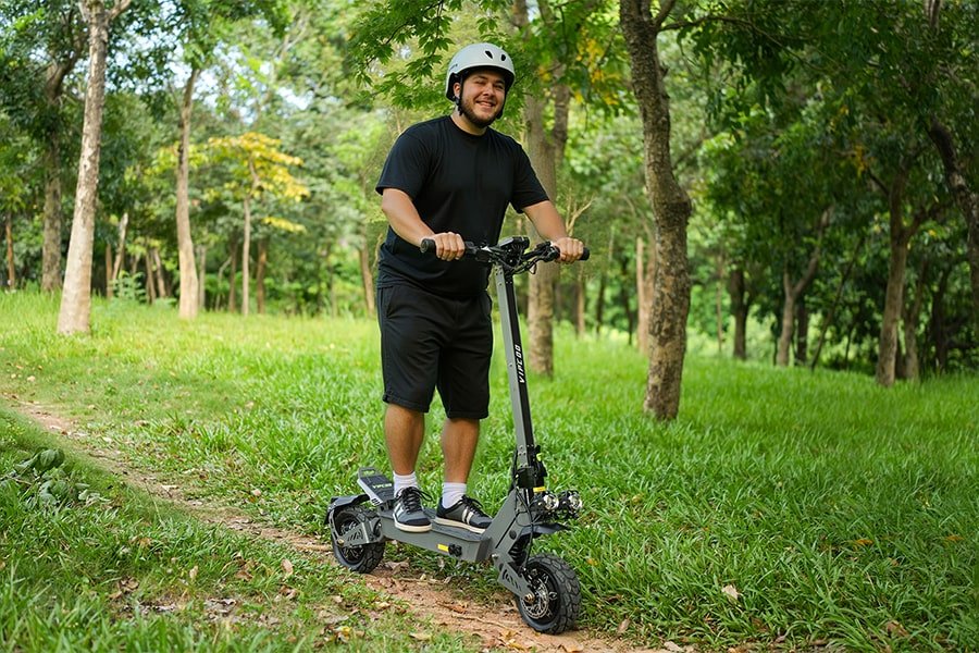 Hombre de pie junto al patinete eléctrico VIPCOO VS9 en un parque