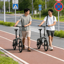 Dos personas con la bicicleta eléctrica plegable YANGOR H19 en color beige por un camino peatonal